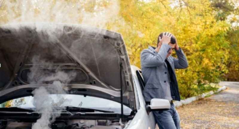 A person stressed out after white fumes are being emitted from his engine