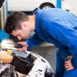 Mechanic examining engine bay with torch